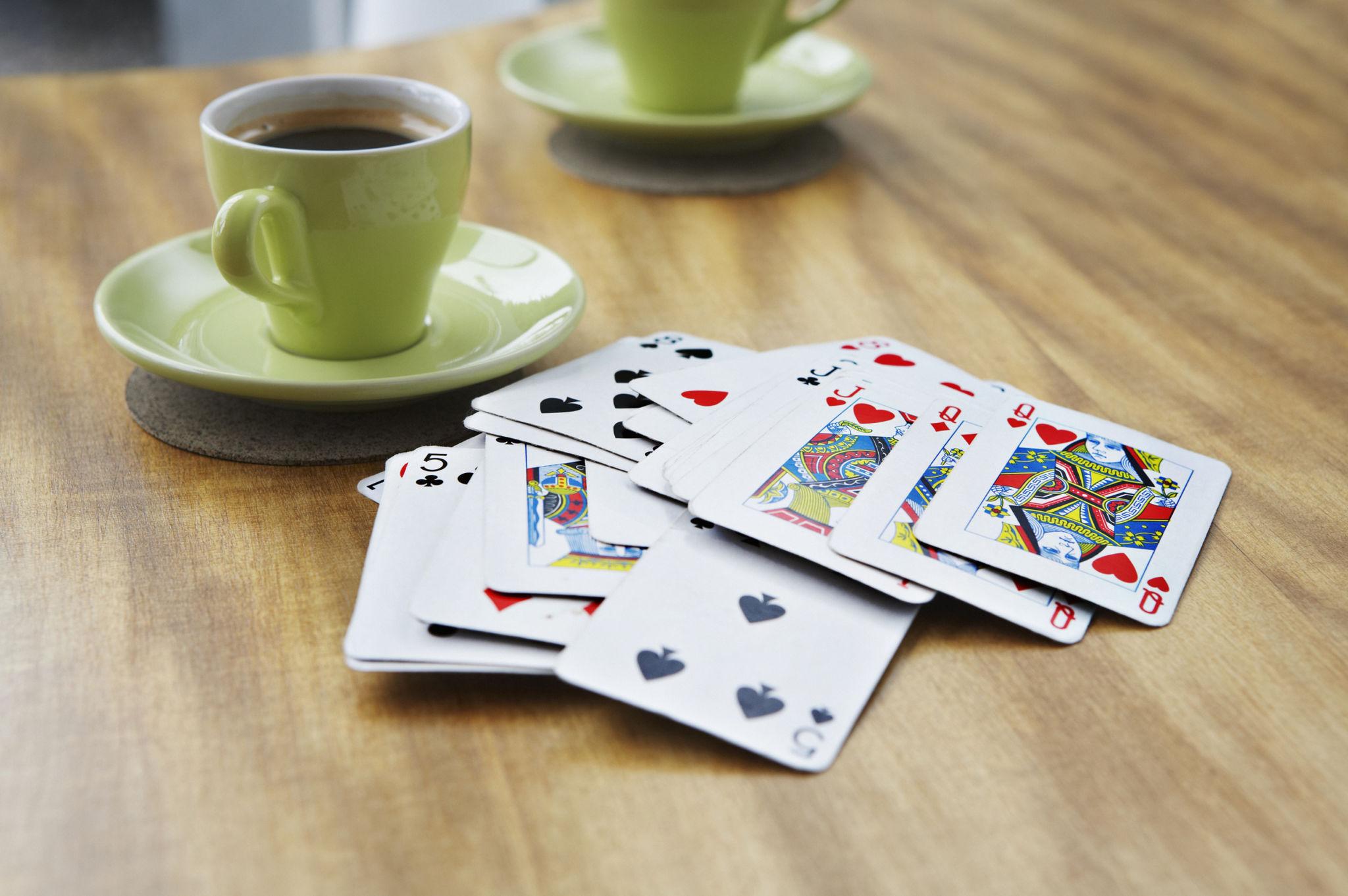 Spielkarten und zwei Kaffeetassen auf einem Tisch als Symbol für gemeinsame Zeit